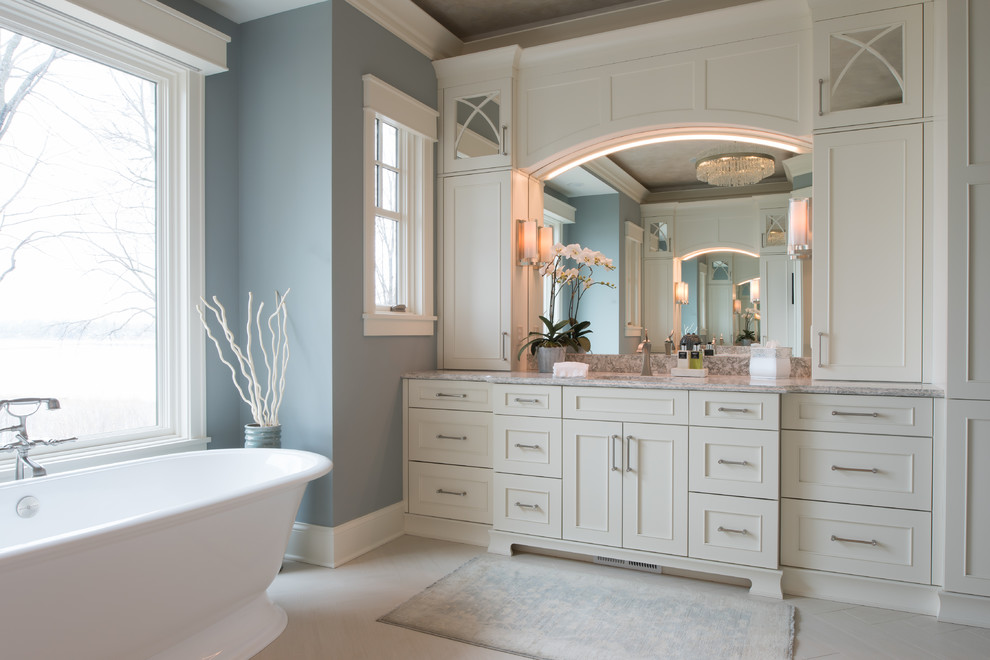Пример оригинального дизайна: ванная комната в классическом стиле с фасадами с утопленной филенкой, отдельно стоящей ванной, синими стенами, врезной раковиной, бежевым полом, серой столешницей и бежевыми фасадами