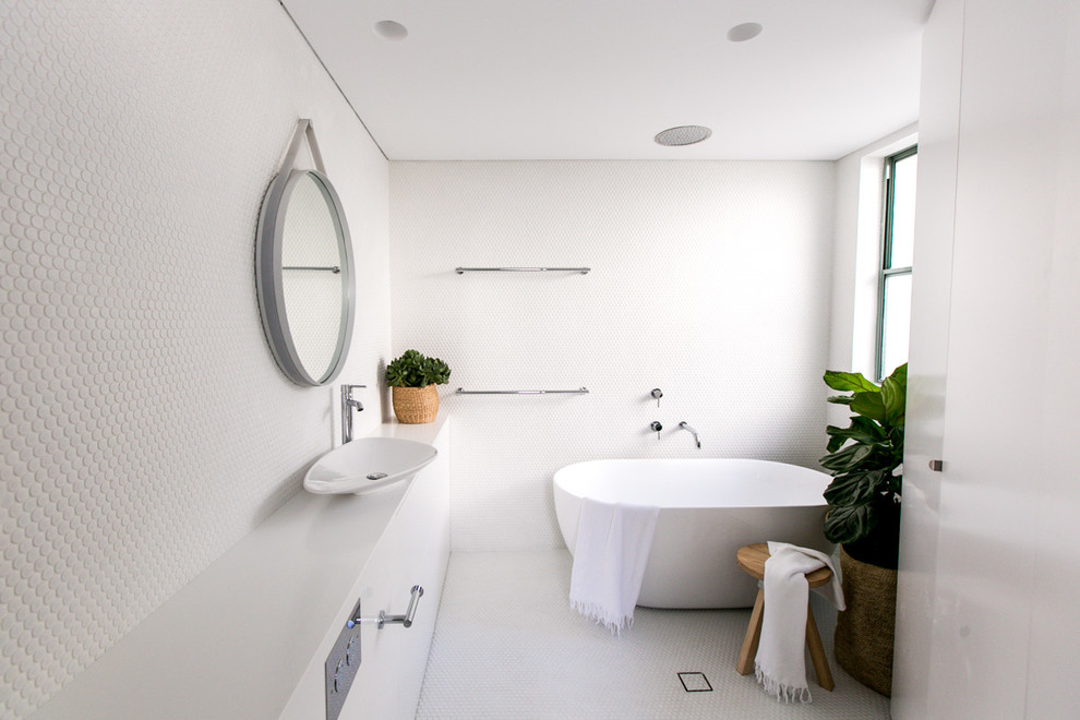 Bathroom - mid-sized contemporary white tile mosaic tile floor bathroom idea in Sydney with white cabinets, solid surface countertops, a wall-mount toilet and a vessel sink