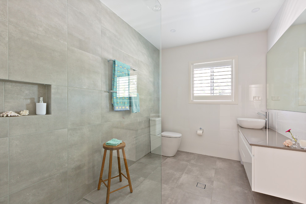 Пример оригинального дизайна: ванная комната в морском стиле с плоскими фасадами, белыми фасадами, угловым душем, унитазом-моноблоком, серой плиткой, цементной плиткой, белыми стенами, бетонным полом, душевой кабиной, настольной раковиной, серым полом, открытым душем и коричневой столешницей