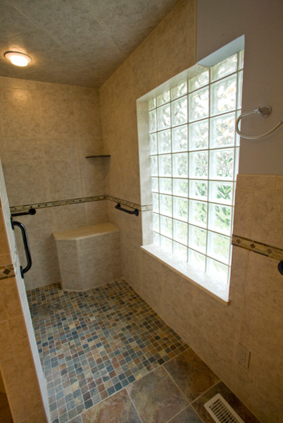 Klassisk inredning av ett mellanstort en-suite badrum, med ett undermonterad handfat, släta luckor, skåp i mörkt trä, marmorbänkskiva, en dusch i en alkov, en toalettstol med hel cisternkåpa, beige kakel, keramikplattor, beige väggar och klinkergolv i keramik
