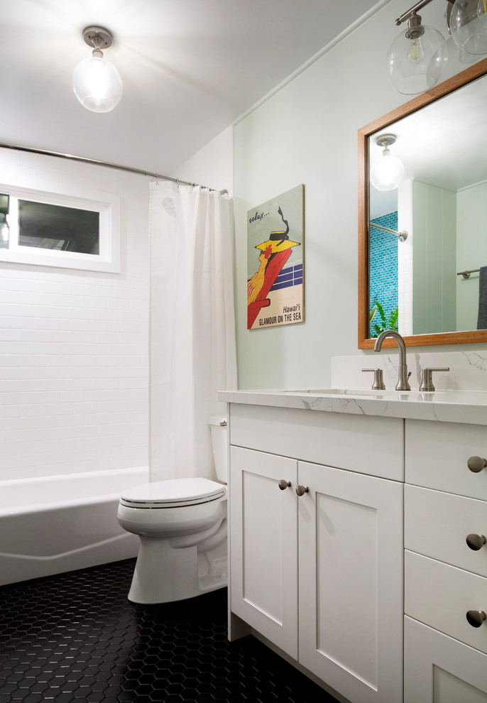 Aménagement d'une salle de bain classique de taille moyenne avec un placard à porte shaker, des portes de placard blanches, une baignoire en alcôve, un combiné douche/baignoire, WC séparés, un carrelage blanc, des carreaux de céramique, un mur gris, un sol en carrelage de porcelaine, un lavabo encastré, un plan de toilette en quartz modifié, un sol noir, une cabine de douche avec un rideau et un plan de toilette blanc.
