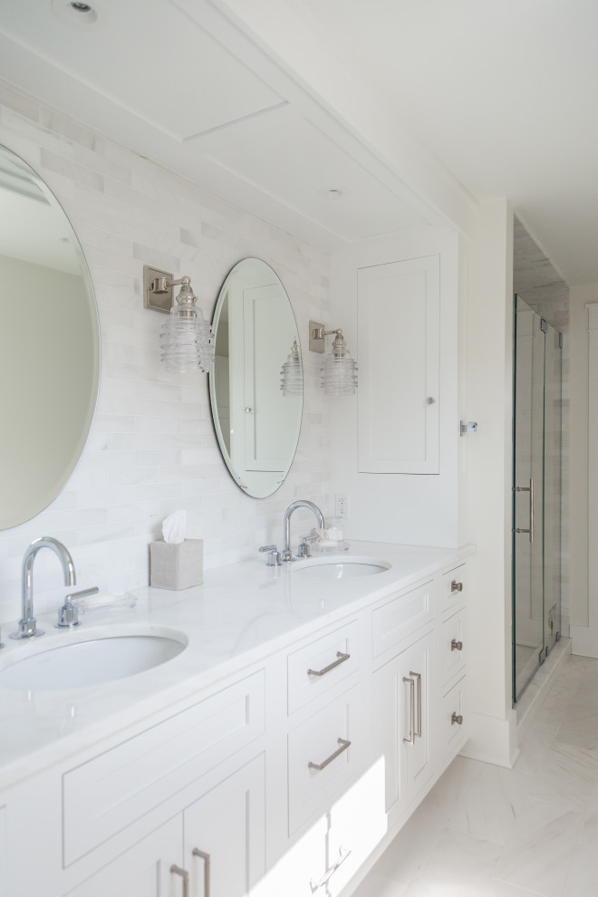Пример оригинального дизайна: ванная комната в морском стиле с фасадами в стиле шейкер, белыми фасадами, белой плиткой, белыми стенами, врезной раковиной, белым полом, белой столешницей, тумбой под две раковины и встроенной тумбой