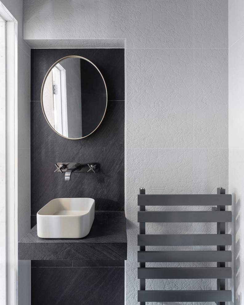 Inspiration för ett litet funkis blå blått badrum med dusch, med våtrum, en vägghängd toalettstol, svart och vit kakel, keramikplattor, svarta väggar, klinkergolv i keramik, ett avlångt handfat, kaklad bänkskiva och svart golv