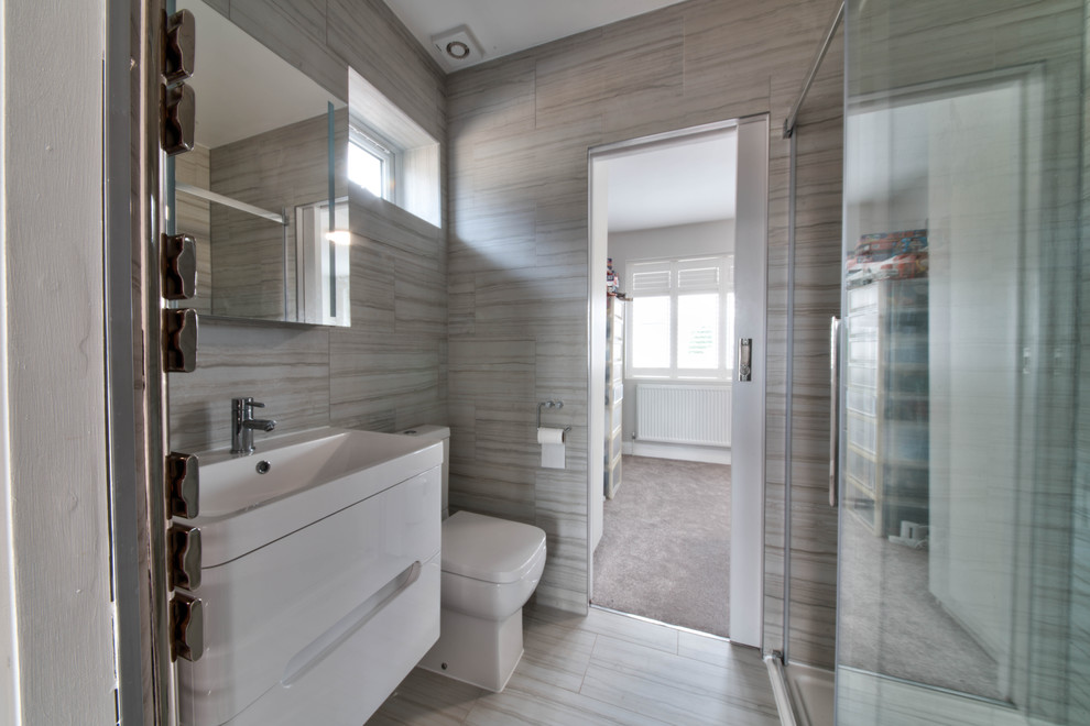 Inredning av ett modernt mellanstort en-suite badrum, med släta luckor, vita skåp, en dusch/badkar-kombination, en toalettstol med separat cisternkåpa, beige kakel, keramikplattor, beige väggar, klinkergolv i porslin, ett nedsänkt handfat, flerfärgat golv och dusch med gångjärnsdörr