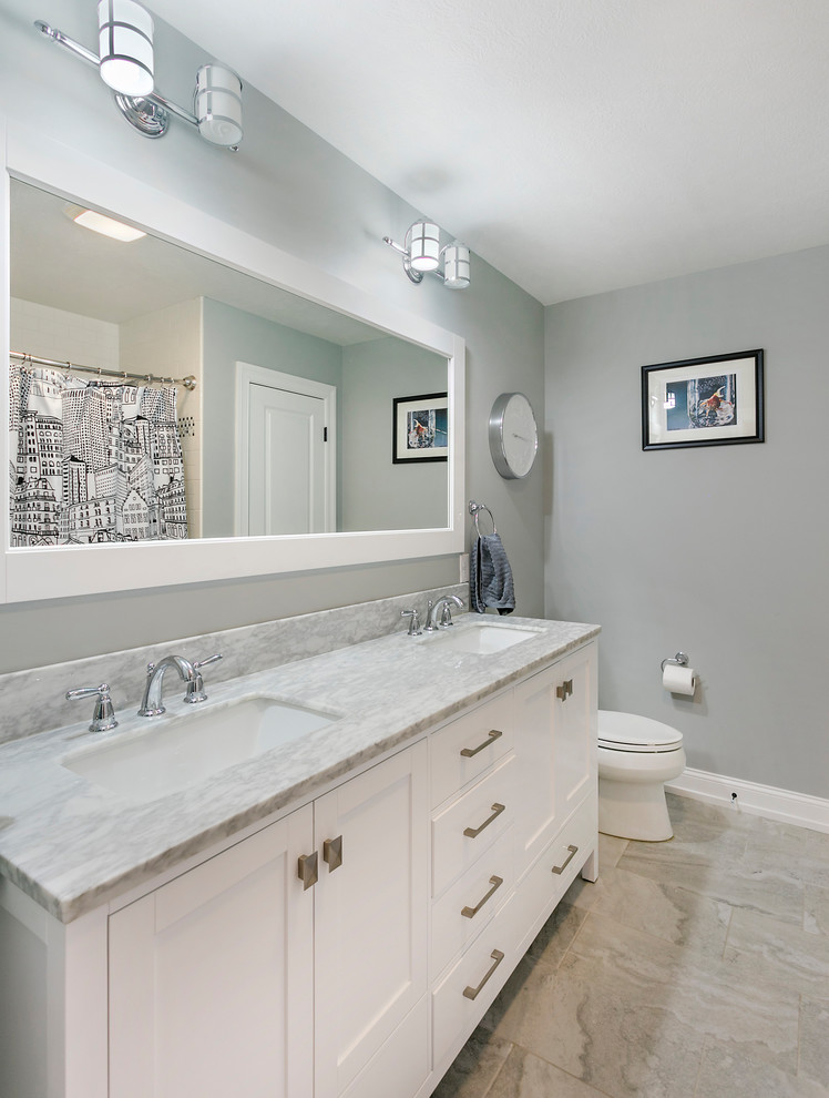 Photo of a medium sized nautical family bathroom in Other with raised-panel cabinets, white cabinets, an alcove bath, a shower/bath combination, a two-piece toilet, white tiles, ceramic tiles, grey walls, ceramic flooring, a submerged sink, marble worktops, grey floors and a shower curtain.