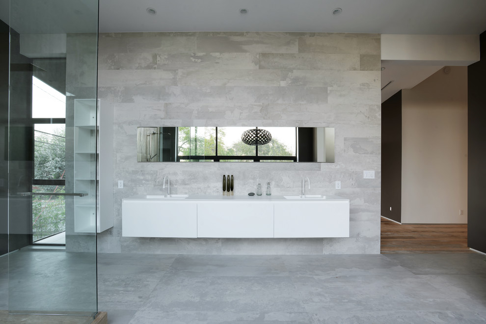 Immagine di una grande stanza da bagno padronale minimal con ante lisce, ante bianche, doccia ad angolo, pareti grigie, pavimento in cemento, lavabo integrato e top in superficie solida