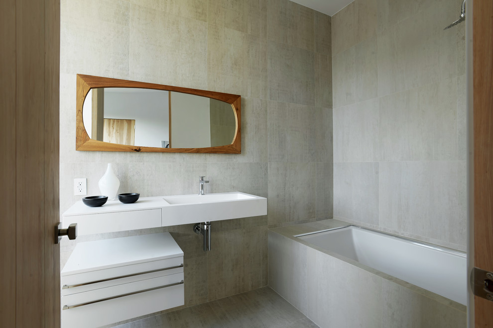 Свежая идея для дизайна: ванная комната среднего размера в современном стиле с плоскими фасадами, белыми фасадами, полновстраиваемой ванной, душем над ванной, бежевой плиткой, керамогранитной плиткой, бежевыми стенами, полом из керамогранита, душевой кабиной, монолитной раковиной, столешницей из искусственного камня, бежевым полом и шторкой для ванной - отличное фото интерьера