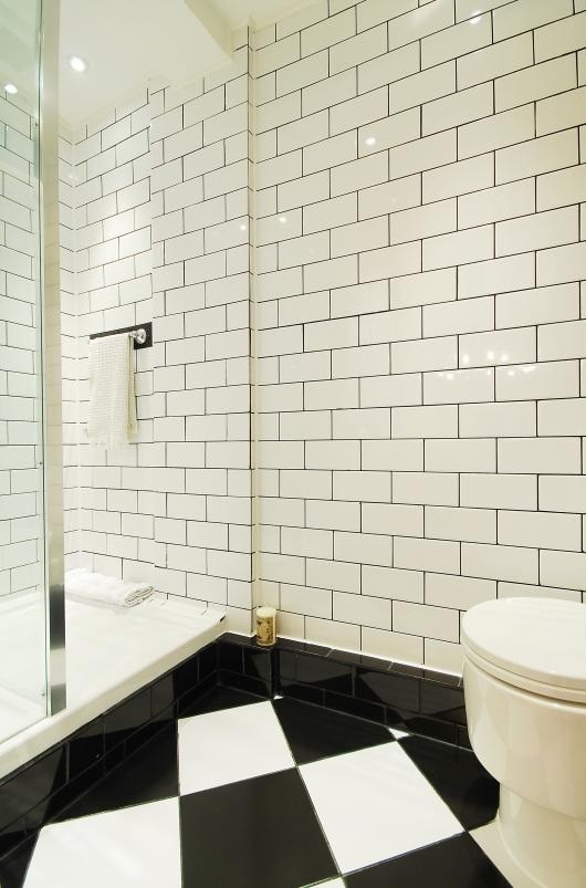 Inspiration for a small modern black tile and ceramic tile ceramic tile doorless shower remodel in London with a console sink, flat-panel cabinets, black cabinets, tile countertops, a one-piece toilet and white walls