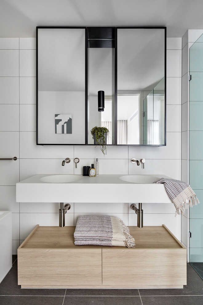 На фото: ванная комната в современном стиле с плоскими фасадами, душем в нише, белой плиткой, белыми стенами, душевой кабиной, подвесной раковиной, душем с распашными дверями и белой столешницей