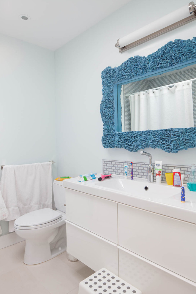 На фото: детская ванная комната в стиле модернизм с монолитной раковиной, плоскими фасадами, белыми фасадами, серой плиткой и белой столешницей