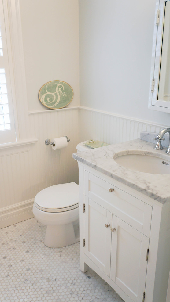 Inredning av ett klassiskt litet badrum med dusch, med ett undermonterad handfat, skåp i shakerstil, vita skåp, marmorbänkskiva, ett badkar i en alkov, en dusch/badkar-kombination, en toalettstol med hel cisternkåpa, vit kakel, grå väggar och marmorgolv