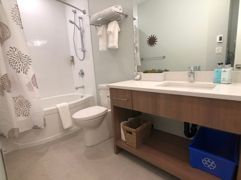 Example of a mid-sized trendy master porcelain tile and beige floor bathroom design in Other with furniture-like cabinets, medium tone wood cabinets, a one-piece toilet, green walls, an undermount sink, quartz countertops and white countertops