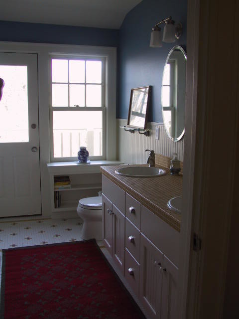 他の地域にある中くらいなトラディショナルスタイルのおしゃれなマスターバスルーム (落し込みパネル扉のキャビネット、白いキャビネット、青い壁、モザイクタイル、オーバーカウンターシンク、黄色いタイル、一体型トイレ	、セラミックタイル、タイルの洗面台、黄色い床、ベージュのカウンター、洗面台2つ、造り付け洗面台、羽目板の壁) の写真