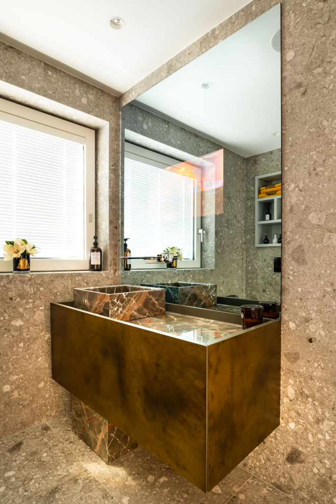 Example of a huge trendy kids' beige tile and marble tile marble floor and beige floor bathroom design in London with flat-panel cabinets, brown cabinets, a wall-mount toilet, beige walls, an integrated sink, marble countertops and multicolored countertops