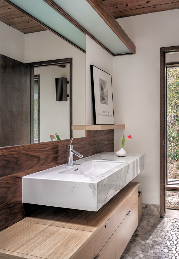 На фото: ванная комната в стиле ретро с плоскими фасадами, светлыми деревянными фасадами, белыми стенами, полом из галечной плитки, врезной раковиной, серым полом и серой столешницей