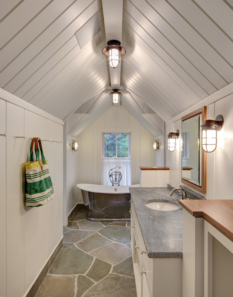 Cette photo montre une salle de bain bord de mer avec un lavabo encastré, des portes de placard blanches, une baignoire indépendante et un mur blanc.
