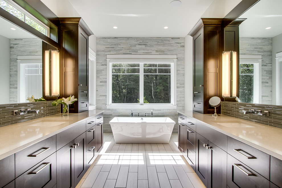 This is an example of a large classic ensuite bathroom in Seattle with shaker cabinets, dark wood cabinets, a freestanding bath, a corner shower, a one-piece toilet, grey tiles, stone tiles, grey walls, porcelain flooring, a built-in sink, engineered stone worktops, grey floors and a hinged door.