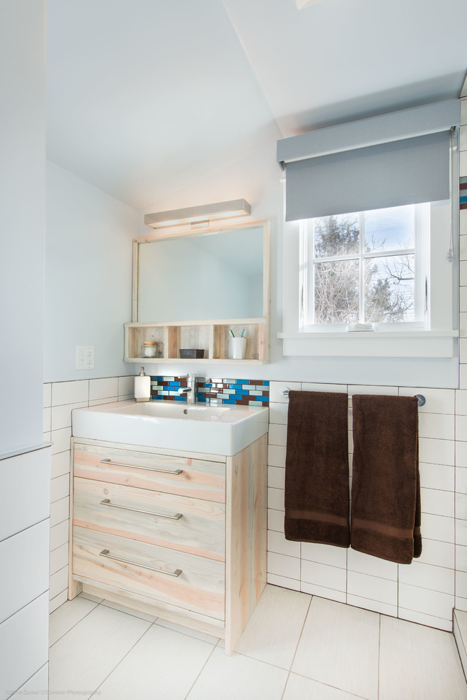 Diseño de cuarto de baño tradicional renovado con armarios con paneles lisos, puertas de armario de madera clara, baldosas y/o azulejos blancos y lavabo integrado