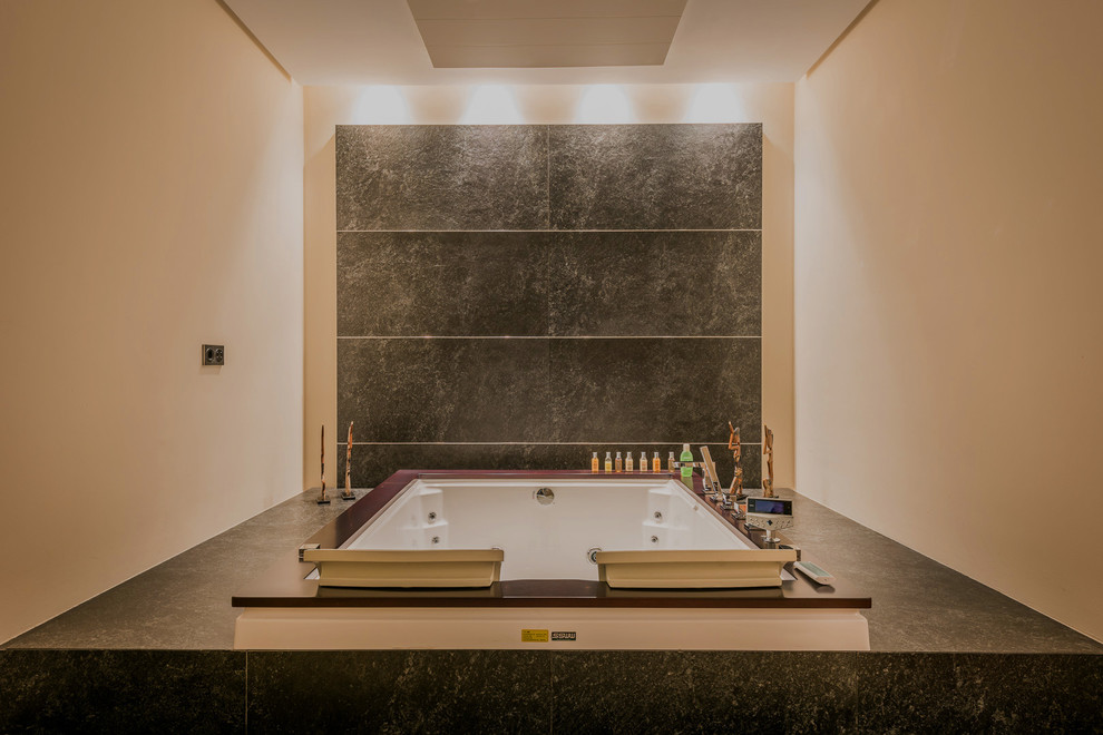 マラガにあるラグジュアリーな広いコンテンポラリースタイルのおしゃれな浴室 (アルコーブ型シャワー、黒いタイル、大理石タイル、ベージュの壁、大理石の床、コンソール型シンク、大理石の洗面台、黒い床、オープンシャワー、大型浴槽) の写真