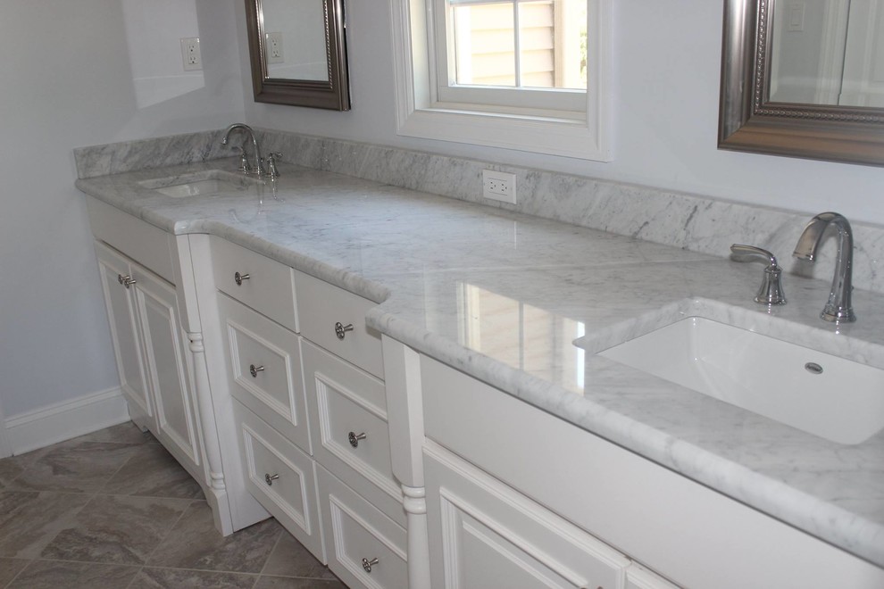 Example of a mid-sized classic master ceramic tile bathroom design in Philadelphia with a drop-in sink, recessed-panel cabinets, white cabinets, marble countertops and white walls