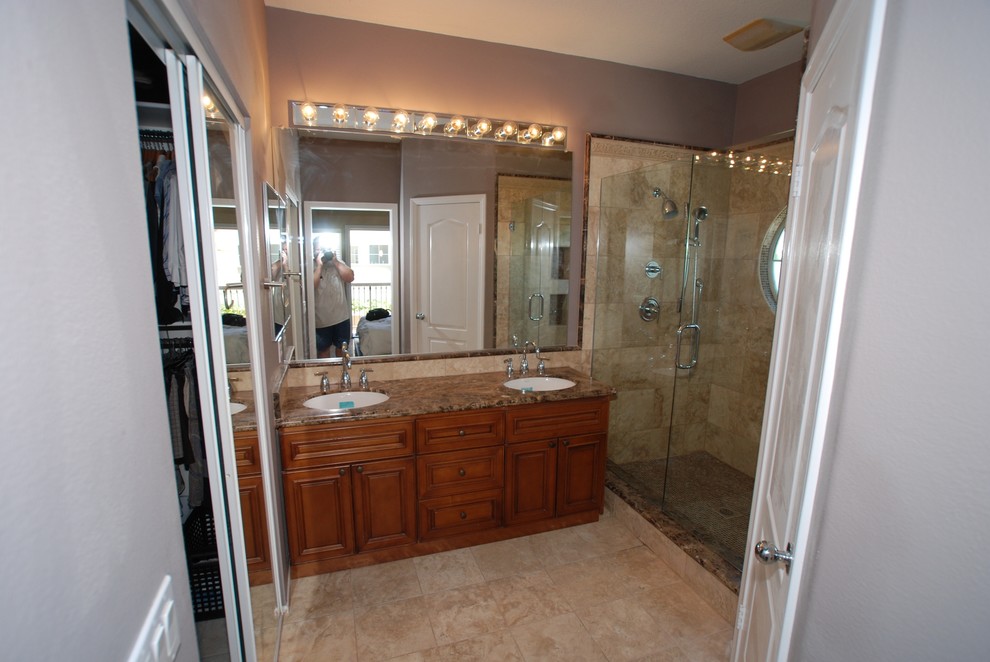 Klassisk inredning av ett mellanstort en-suite badrum, med ett undermonterad handfat, luckor med upphöjd panel, skåp i mörkt trä, marmorbänkskiva, en dusch i en alkov, en toalettstol med separat cisternkåpa, stenkakel, beige väggar och travertin golv