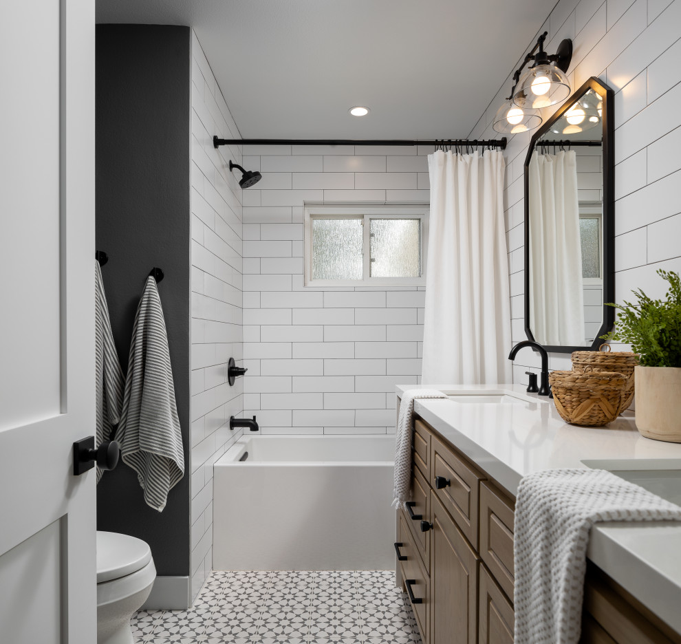 Foto på ett vintage vit en-suite badrum, med luckor med upphöjd panel, bruna skåp, ett badkar i en alkov, en dusch/badkar-kombination, vit kakel, tunnelbanekakel, grå väggar, ett undermonterad handfat, flerfärgat golv och dusch med duschdraperi