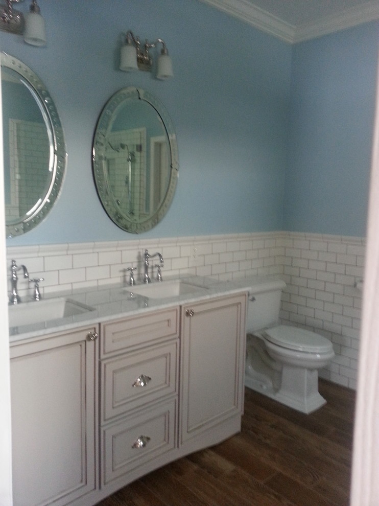 Foto på ett mellanstort vintage en-suite badrum, med luckor med profilerade fronter, vita skåp, ett badkar med tassar, en hörndusch, vit kakel, tunnelbanekakel, blå väggar, mellanmörkt trägolv, ett undermonterad handfat, marmorbänkskiva, blått golv och dusch med gångjärnsdörr