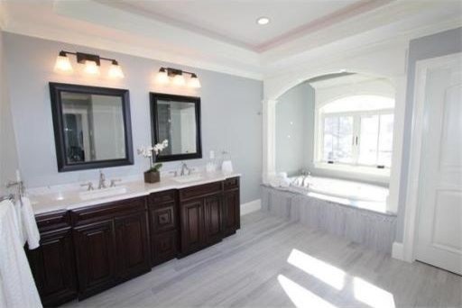 Cette image montre une grande salle de bain principale design en bois foncé avec un placard avec porte à panneau surélevé, une baignoire posée, un mur gris, un sol en marbre, un lavabo encastré, un plan de toilette en quartz modifié et un sol gris.