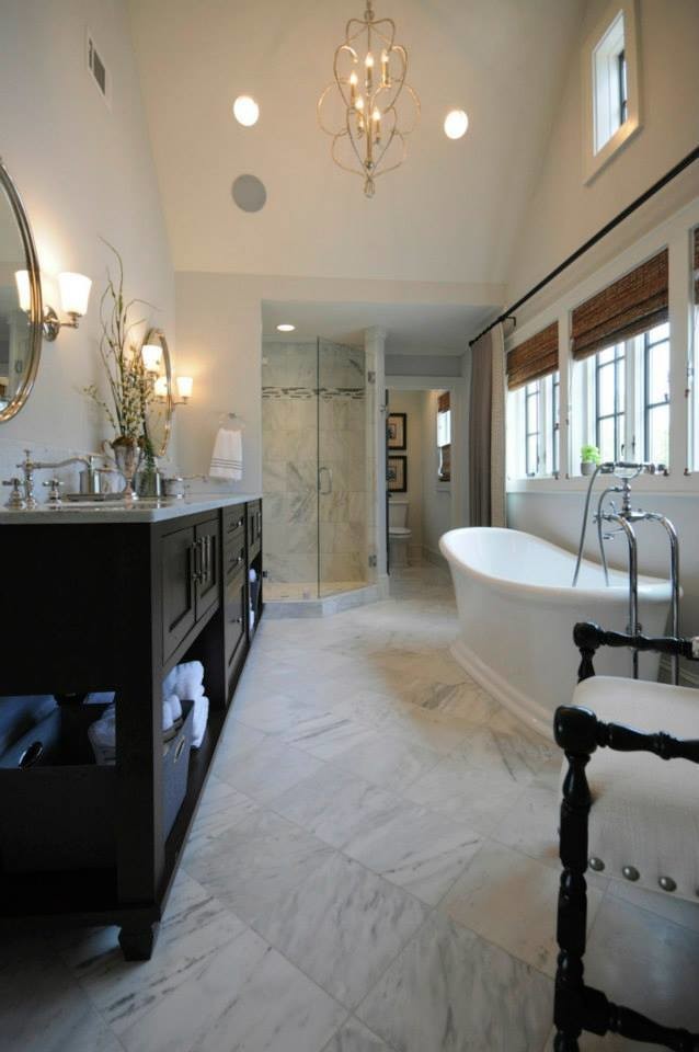Immagine di una grande stanza da bagno chic con ante in stile shaker, ante nere, vasca freestanding, doccia ad angolo, piastrelle in pietra, pareti grigie, pavimento in marmo e top in marmo