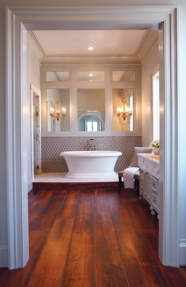Inspiration för ett mellanstort vintage vit vitt en-suite badrum, med luckor med infälld panel, ett fristående badkar, beige väggar, mörkt trägolv, ett integrerad handfat, marmorbänkskiva, vita skåp, keramikplattor och brunt golv