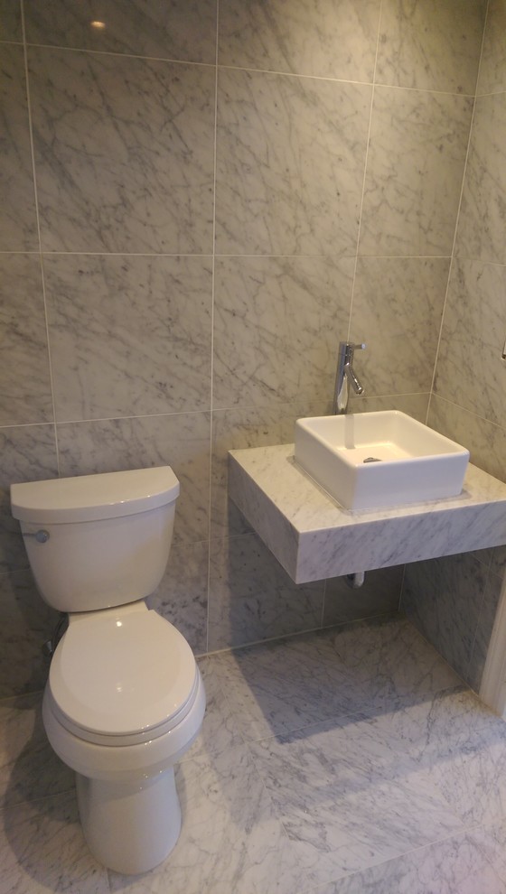 Inspiration for a mid-sized modern 3/4 gray tile, white tile and porcelain tile marble floor bathroom remodel in New York with a one-piece toilet, beige walls, a vessel sink and marble countertops