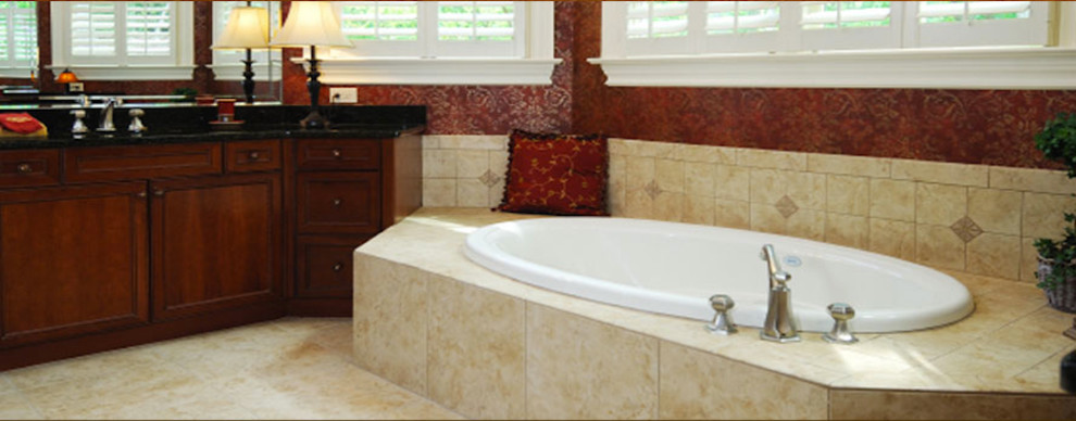 Photo of a large traditional ensuite bathroom in DC Metro with recessed-panel cabinets, a built-in bath, beige tiles, red walls, marble flooring, a submerged sink, granite worktops, dark wood cabinets and stone tiles.