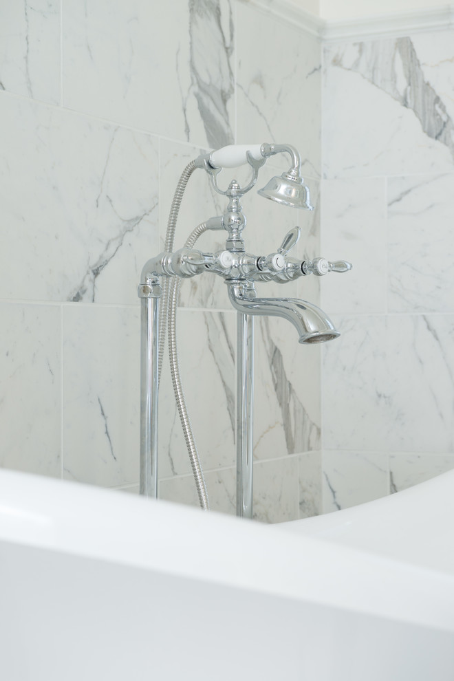 Klassisk inredning av ett mellanstort en-suite badrum, med möbel-liknande, vita skåp, marmorbänkskiva, ett fristående badkar, en dusch i en alkov, vit kakel, porslinskakel, vita väggar och klinkergolv i porslin