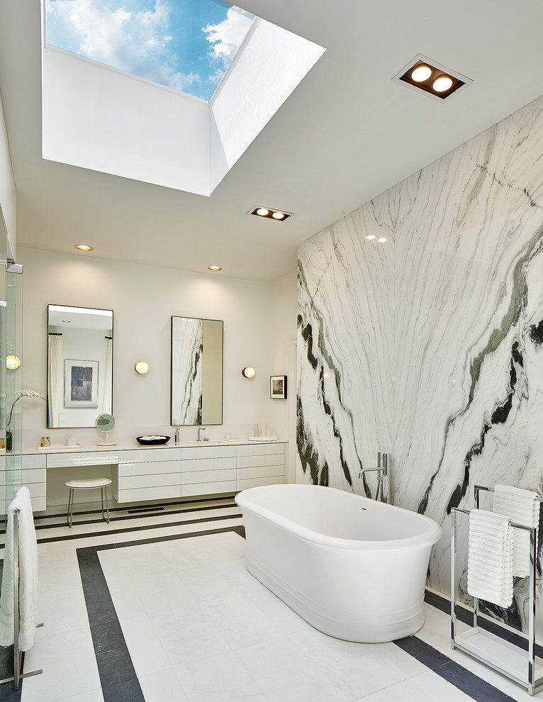 Идея дизайна: огромная главная ванная комната в стиле модернизм с плоскими фасадами, белыми фасадами, отдельно стоящей ванной, душем без бортиков, инсталляцией, черно-белой плиткой, плиткой из листового стекла, белыми стенами, мраморным полом, монолитной раковиной, столешницей из кварцита, белым полом и душем с распашными дверями