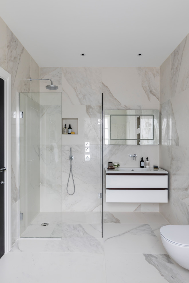 Inspiration for a small contemporary bathroom in London with flat-panel cabinets, white cabinets, a one-piece toilet, black and white tiles, white tiles, marble tiles, white walls, marble flooring, a wall-mounted sink, solid surface worktops, white floors and an open shower.