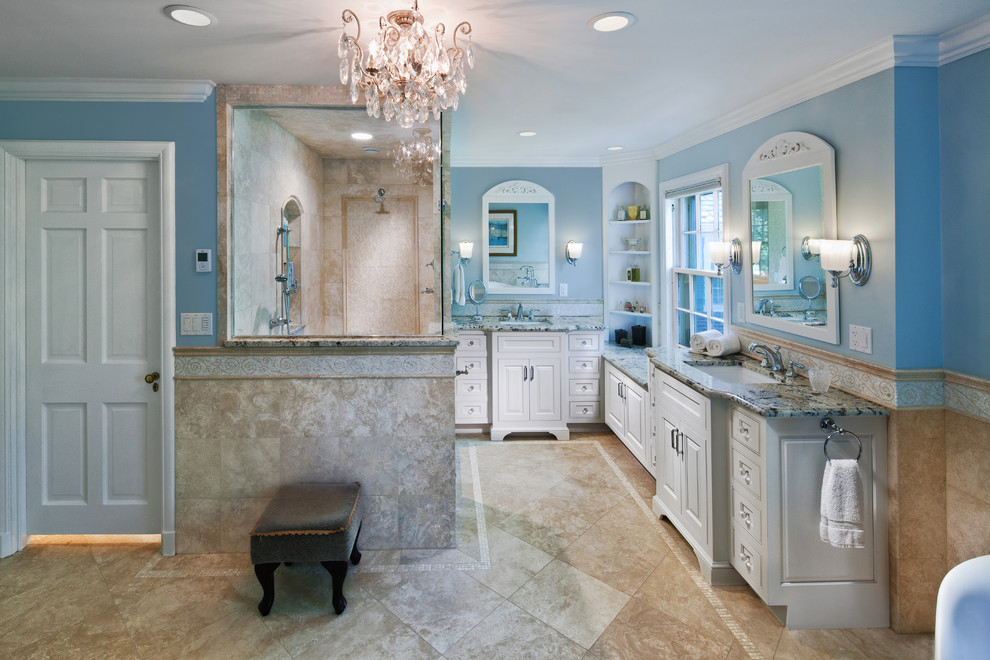 Large classic ensuite bathroom in Cleveland with a submerged sink, beaded cabinets, white cabinets, granite worktops, a freestanding bath, a corner shower, a one-piece toilet, beige tiles, stone tiles, blue walls, travertine flooring and beige floors.