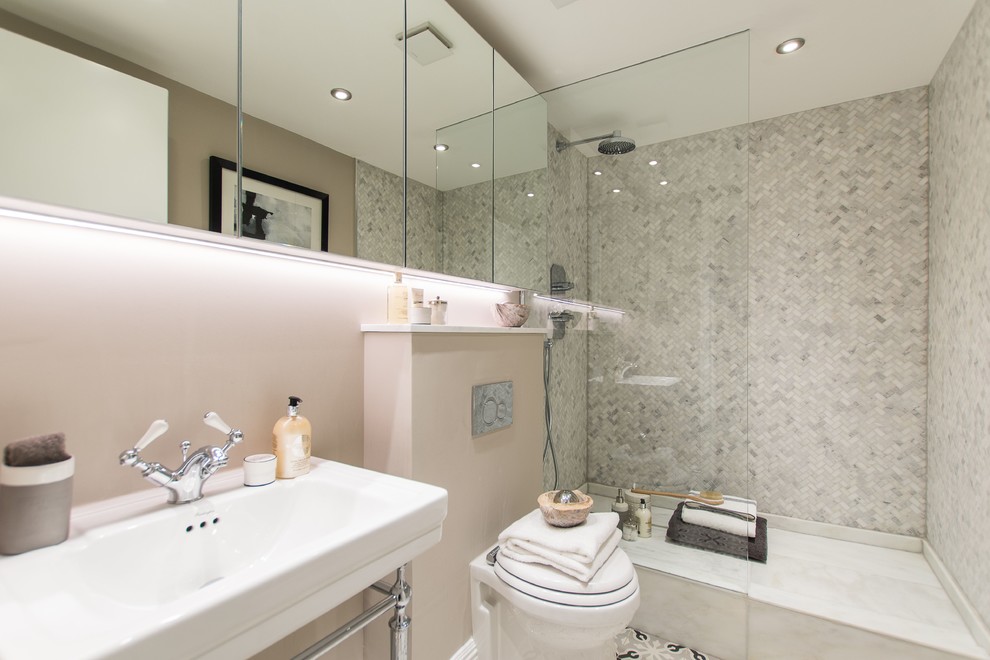 Medium sized contemporary ensuite bathroom in London with flat-panel cabinets, a corner shower, a wall mounted toilet, white tiles, marble tiles, beige walls, ceramic flooring, a pedestal sink, marble worktops, multi-coloured floors and a hinged door.
