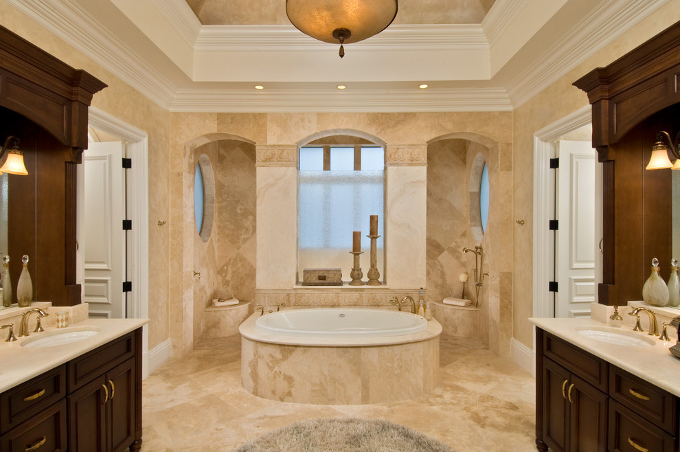 Example of an island style beige tile drop-in bathtub design in Miami with an undermount sink, recessed-panel cabinets and dark wood cabinets