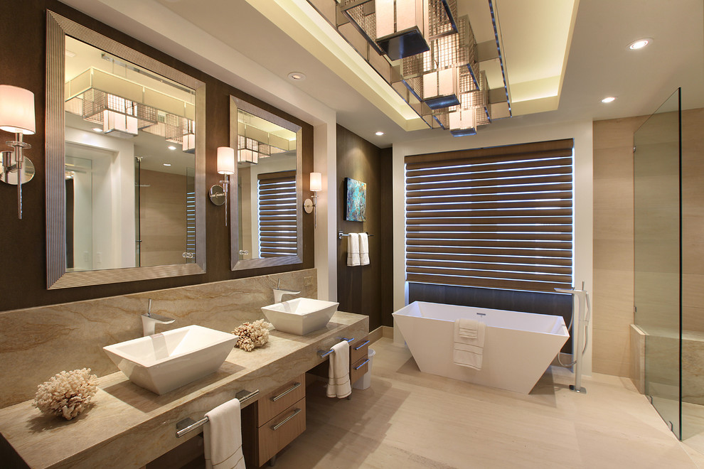 Inspiration for a large contemporary ensuite bathroom in Miami with a vessel sink, flat-panel cabinets, light wood cabinets, a freestanding bath, a built-in shower, beige tiles, marble worktops, ceramic tiles, beige walls, limestone flooring and an open shower.