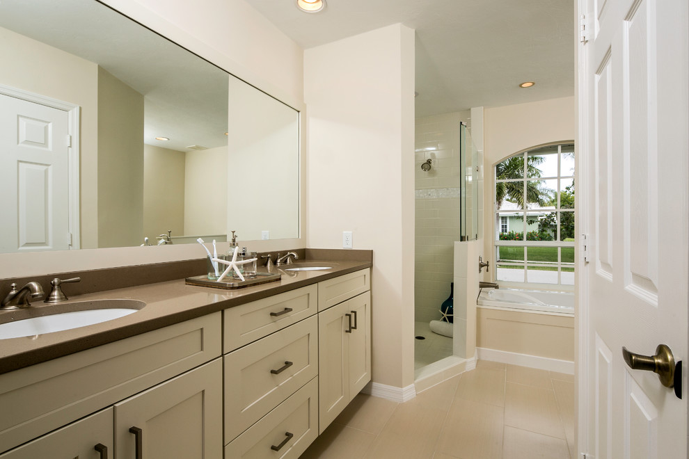Beach style master beige tile and porcelain tile porcelain tile bathroom photo in Tampa with an undermount sink, shaker cabinets, beige cabinets, quartz countertops and beige walls