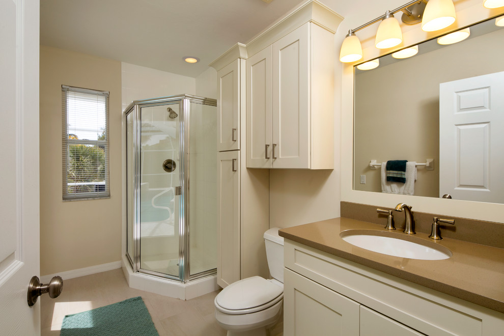 Exemple d'une salle de bain bord de mer avec un lavabo encastré, une douche d'angle, un placard à porte shaker, des portes de placard beiges, un plan de toilette en quartz modifié, un carrelage beige, des carreaux de porcelaine, un mur beige et un sol en carrelage de porcelaine.