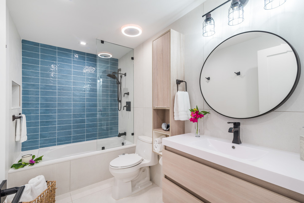 Photo of a medium sized coastal family bathroom with flat-panel cabinets, light wood cabinets, a built-in shower, a one-piece toilet, white tiles, porcelain tiles, white walls, porcelain flooring, a submerged sink, engineered stone worktops, white floors, a hinged door, white worktops and an alcove bath.