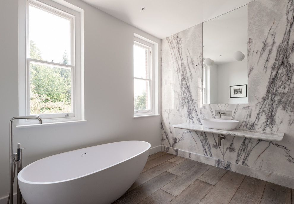 Inspiration for a contemporary bathroom in London with a vessel sink, white tiles, stone slabs, white walls and medium hardwood flooring.