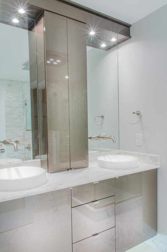 Cette photo montre une salle de bain principale tendance de taille moyenne avec une vasque, un placard à porte plane, des portes de placard grises, un plan de toilette en marbre, un mur blanc et un sol en carrelage de céramique.