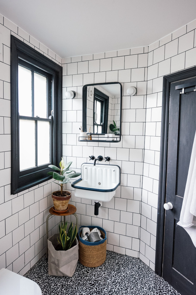 Стильный дизайн: детская ванная комната среднего размера в скандинавском стиле с накладной ванной, душем над ванной, унитазом-моноблоком, белой плиткой, керамической плиткой, белыми стенами, полом из терраццо, подвесной раковиной, черным полом, душем с распашными дверями и тумбой под одну раковину - последний тренд
