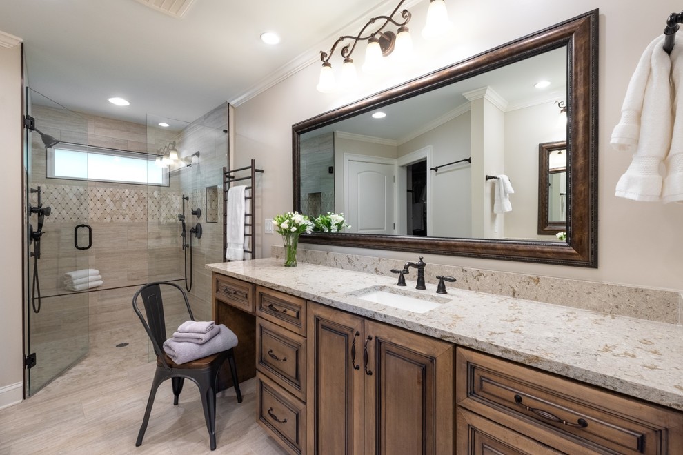 Example of a classic gray tile gray floor walk-in shower design in Atlanta with raised-panel cabinets, medium tone wood cabinets, gray walls, an undermount sink, a hinged shower door and beige countertops