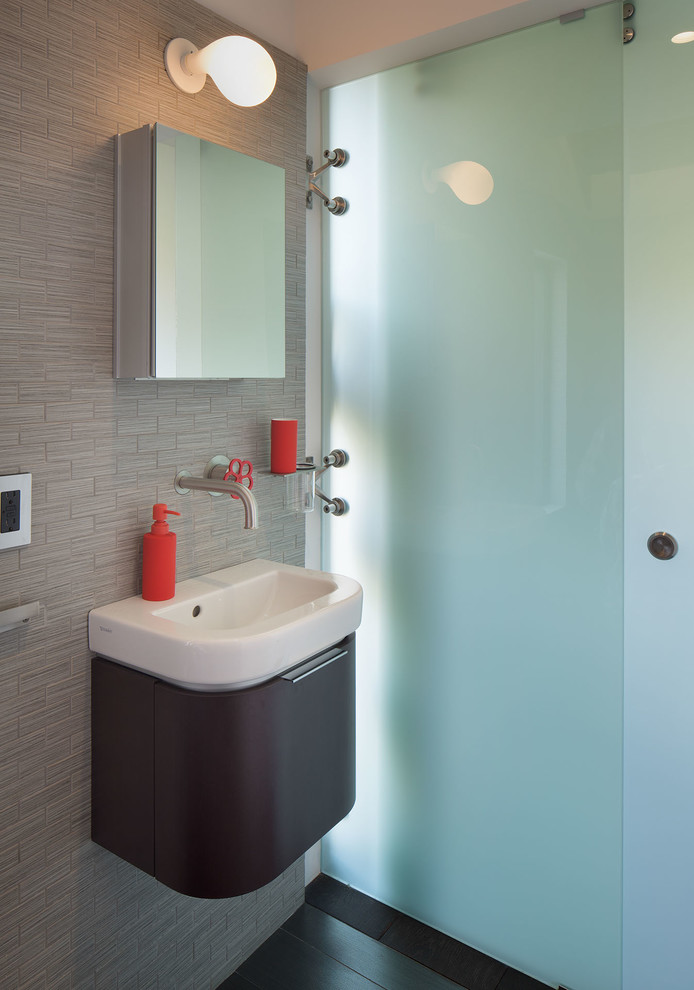 На фото: ванная комната в современном стиле с консольной раковиной, плоскими фасадами, темными деревянными фасадами и серой плиткой с
