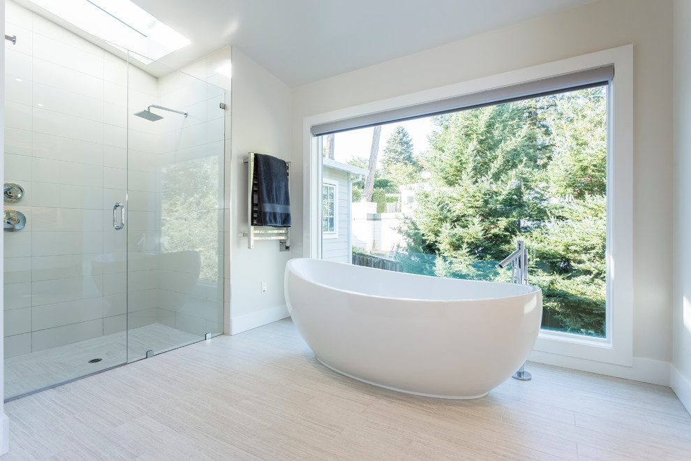 Immagine di una stanza da bagno contemporanea con vasca freestanding, doccia a filo pavimento, piastrelle bianche e pareti bianche