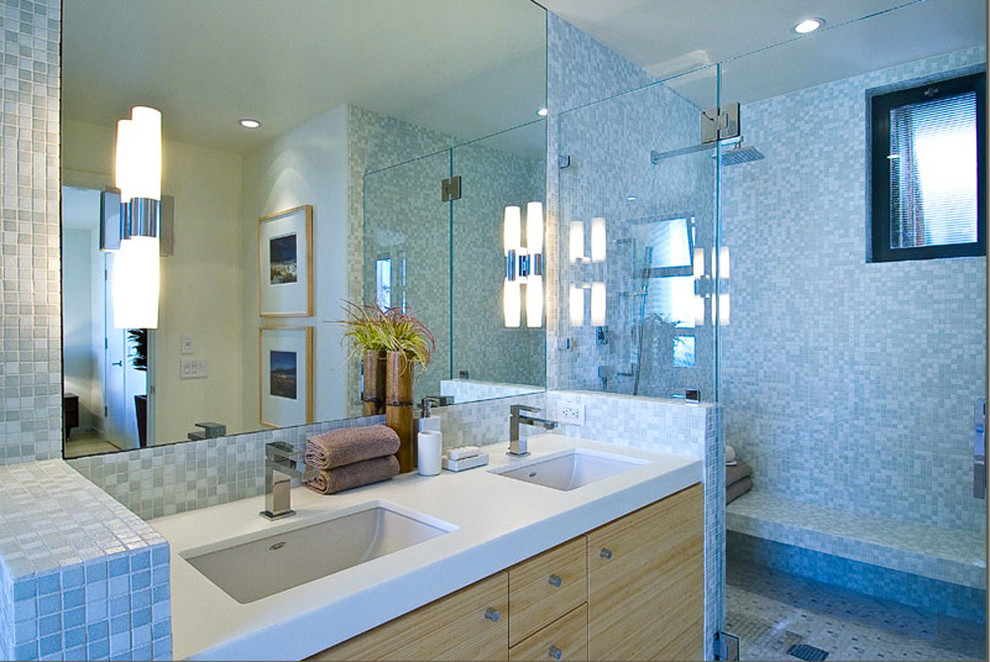 Cette image montre une douche en alcôve principale design en bois clair avec un lavabo encastré, un placard à porte plane, un carrelage bleu, un carrelage en pâte de verre, un mur bleu et un sol en marbre.