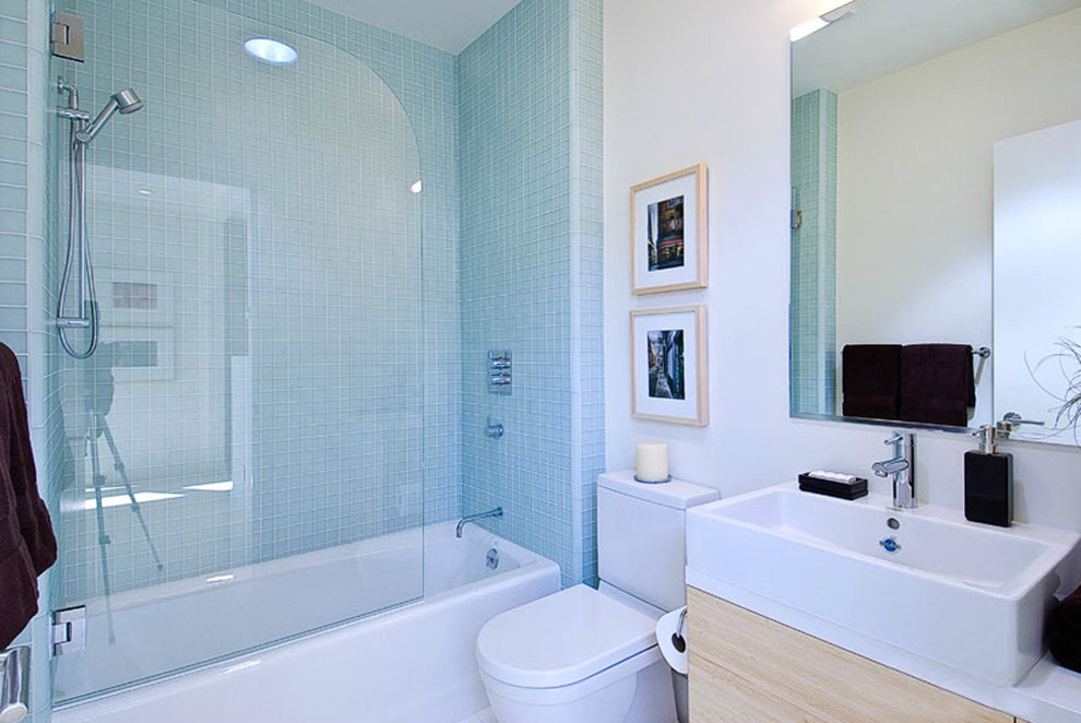 Immagine di una stanza da bagno padronale design con lavabo a bacinella, ante lisce, ante in legno chiaro, vasca da incasso, WC a due pezzi, piastrelle blu, piastrelle di vetro e pareti bianche